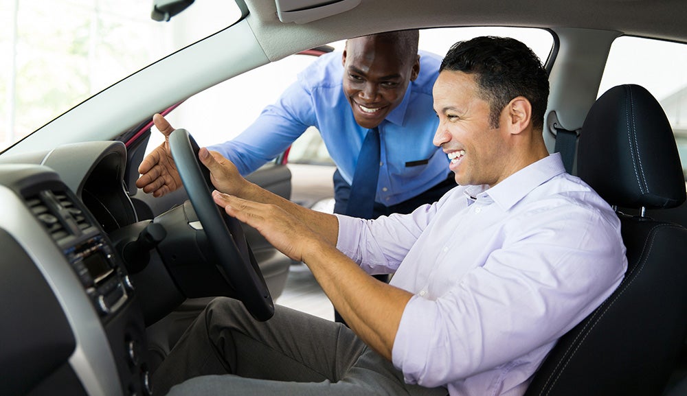Customer receiving a vehicle walkthrough from a salesperson inside a car during a test drive.