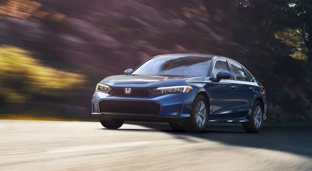 Blue 2026 Honda Civic LX driving down an open road.