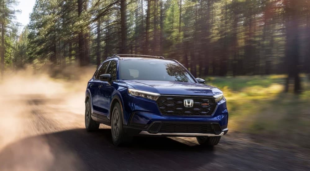 A blue 2026 Honda CR-V TrailSport Hybrid driving offroad.