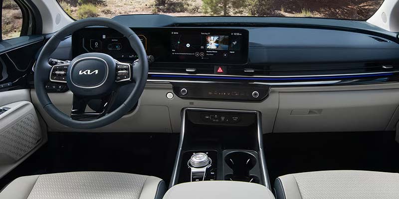 Modern car interior with a minimalist dashboard, digital display screens, multifunction steering wheel, and center console with cup holders and controls.
