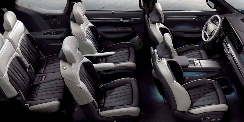 A high-angle view of a modern SUV interior featuring three rows of premium two-tone seats with dark gray ribbed centers and light gray trim.