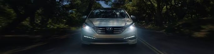 Sonata driving on a rural road at night with headlights on