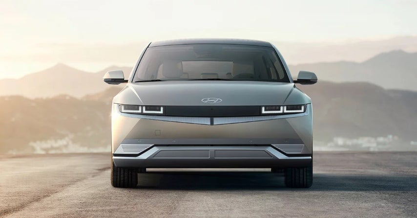 Front view of a silver Hyundai IONIQ 5 electric vehicle parked on a road with mountains in the background.