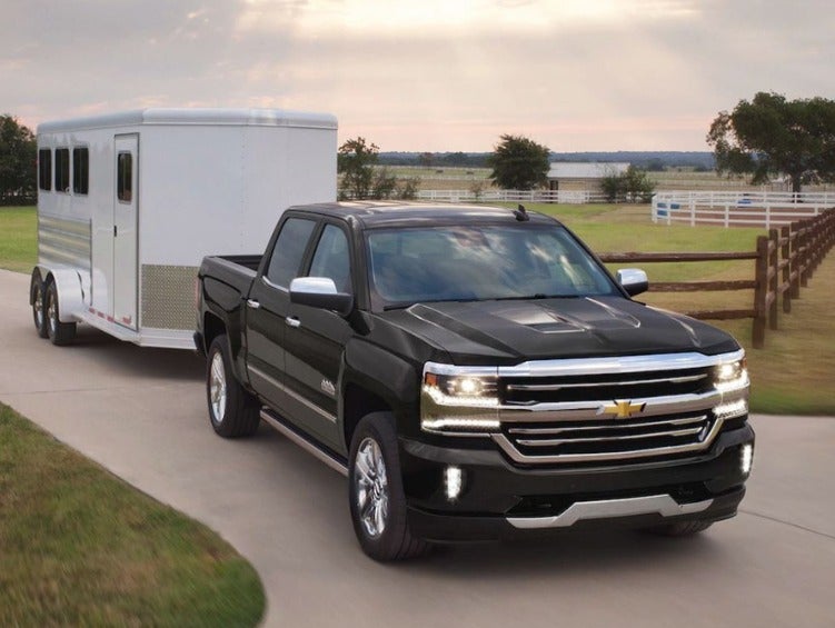Chevy pickup truck pulling a horse trailer from a ranch