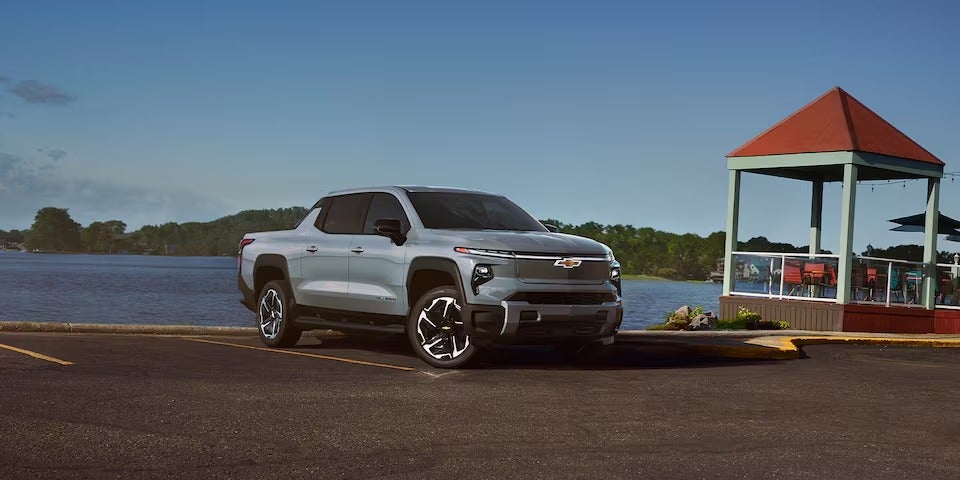 2025 Chevrolet Silverado EV parked in front of a lake on a sunny day