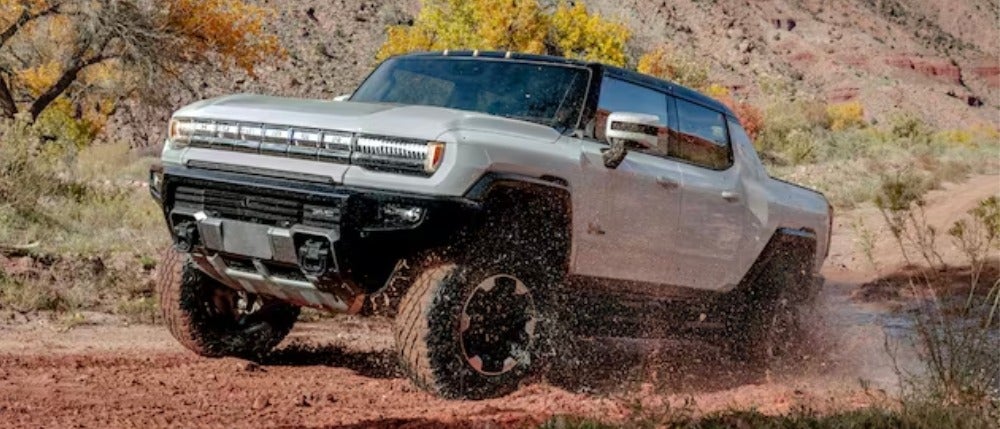 Hummer EV pickup driving through a deep puddle in the desert