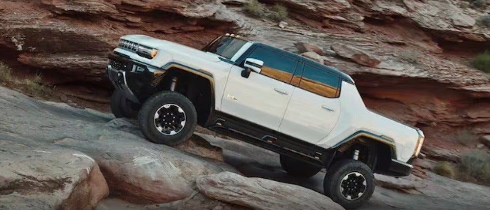 Hummer EV pickup driving over rocks off road in the desert