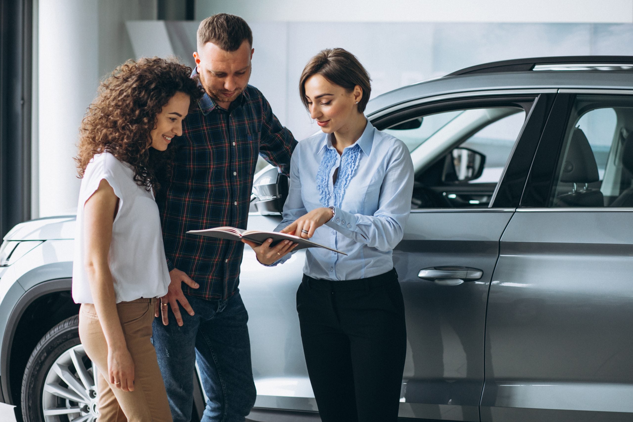 A young couple discusses options with a car saleswoman in a showroom