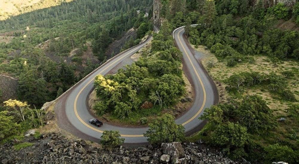 A black 2015 Chevy Colorado is shown driving on a winding mountain road.
