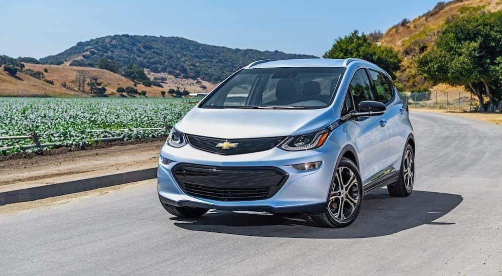 A light blue 2018 Chevy Bolt EV is shown parked on an open road.