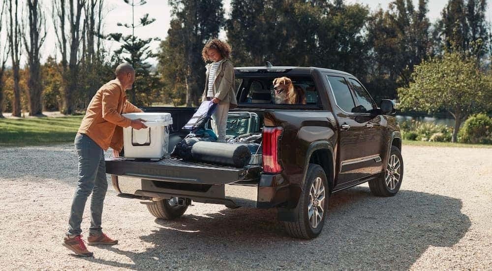A family unloading camping gear from the back of a black 2024 Toyota Tundra.