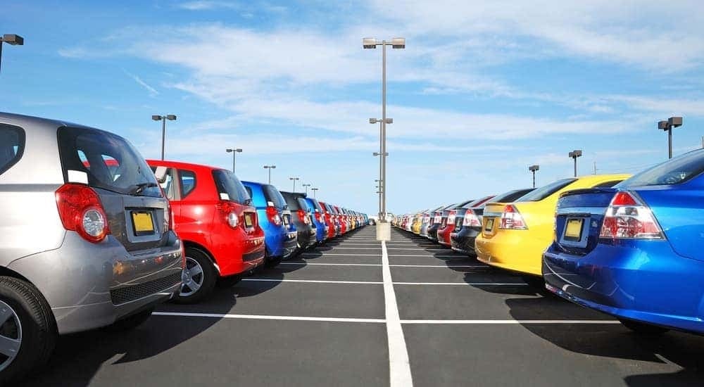 A row of cars are shown parked on a dealership lot.