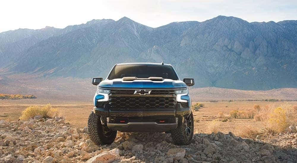 A blue 2024 Chevy Silverado 1500 ZR2 is parked in an open field.
