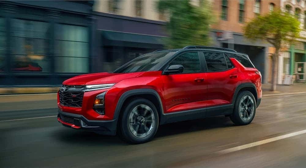Red 2026 Chevy Equinox RS for sale driving down a city street.