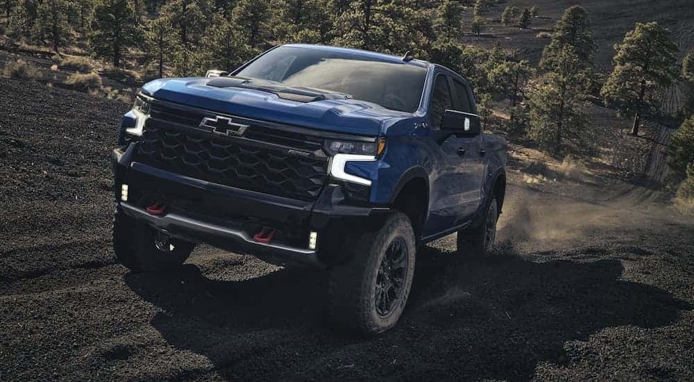 A blue 2026 Chevy Silverado 1500 off-roading up a steep hill