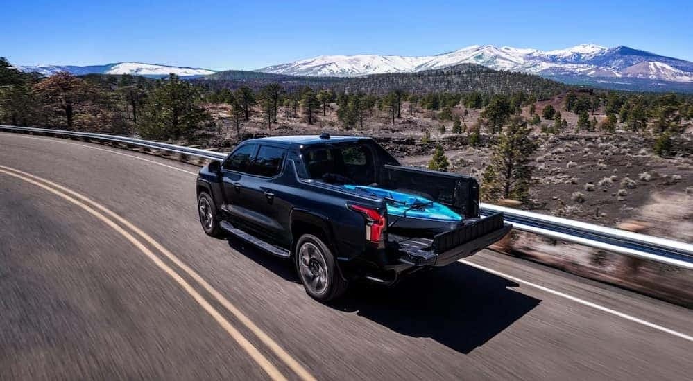 A blue 2025 Chevy Silverado 1500 EV RST driving on a highway.