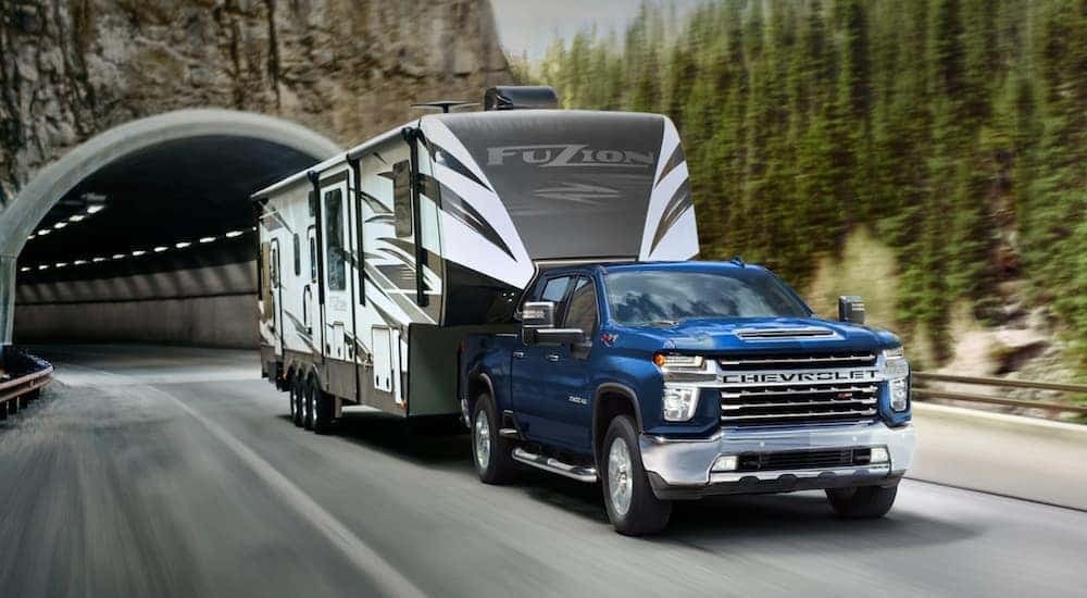 A blue 2021 Chevy Silverado 2500 HD Z71 is shown towing a trailer.