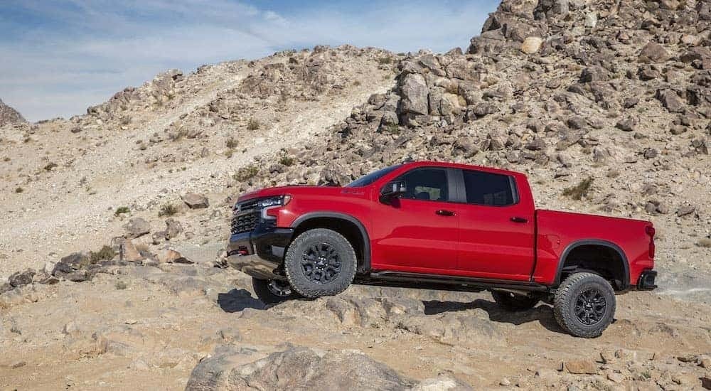 A red 2022 Chevy Silverado 1500 ZR2 is shown from the side while off-road after leaving a Chevy Silverado dealer near Chelsea, AL.
