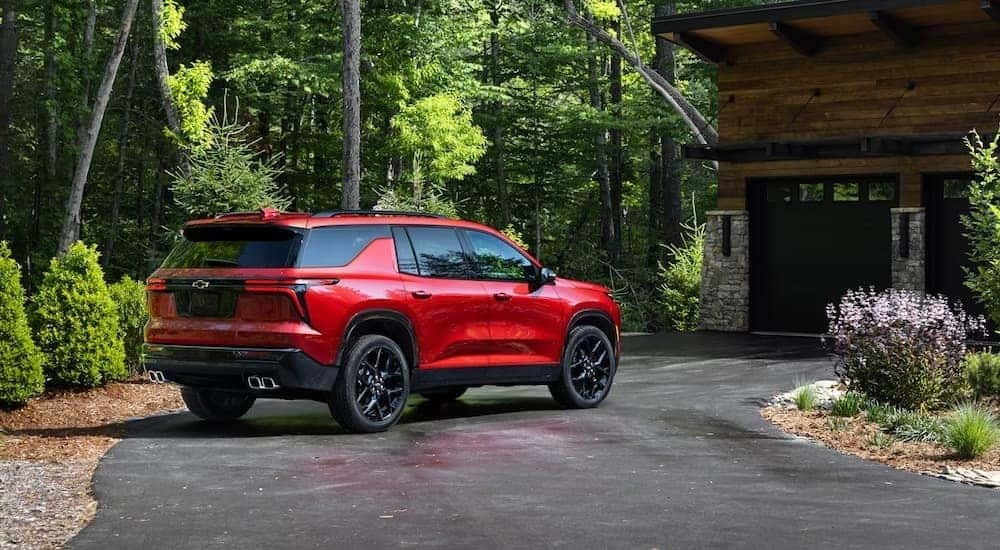 A red 2024 Chevy Traverse RS is parked in a driveway after leaving a car dealer.
