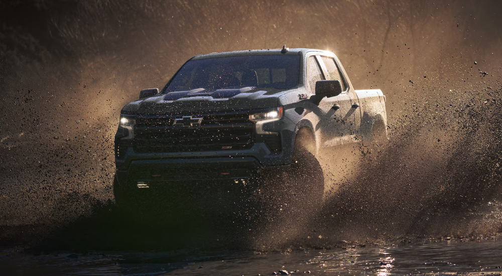 Green 2026 Chevy Silverado 2500 HD driving through mud