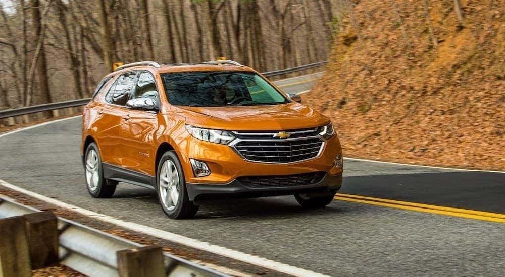 An orange 2018 Chevy Equinox is driving to look at used Chevy SUVs for sale