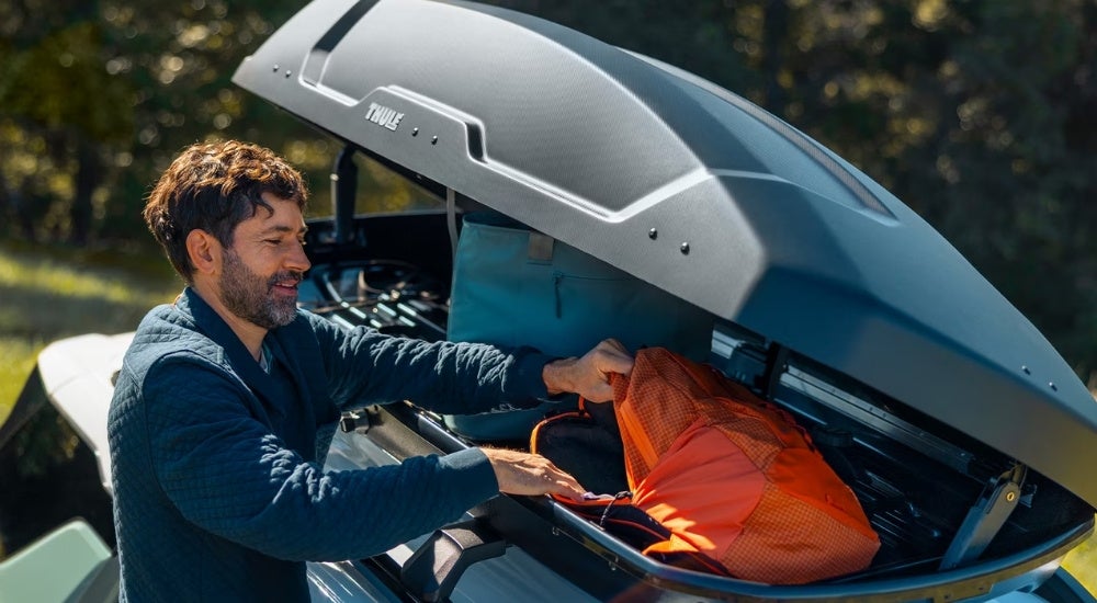 Person loading gear into a roof box on a green 2026 Chevy Equinox ACTIV
