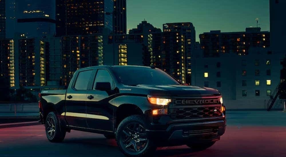 A black 2024 Chevy Silverado 1500 Custom looking at trucks for sale.