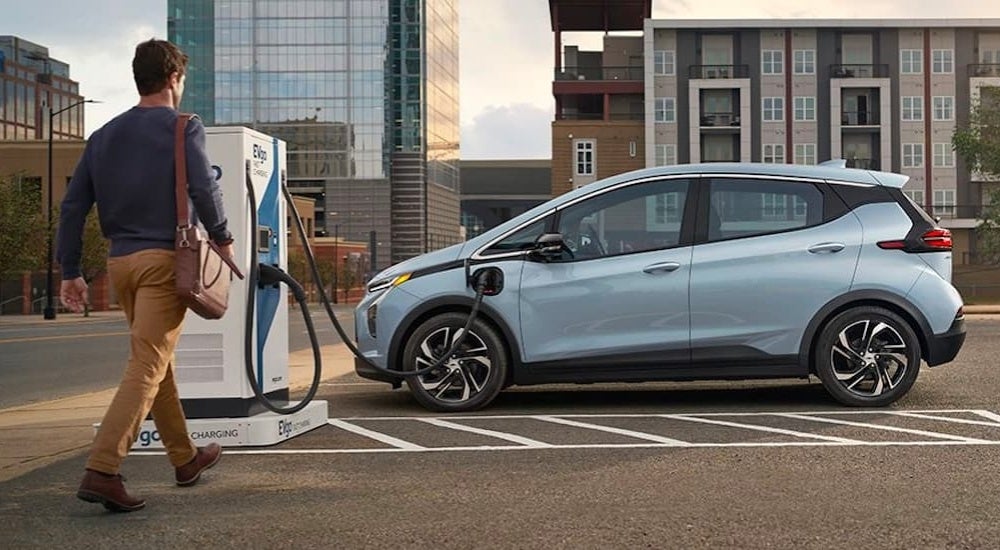 Blue 2023 Chevy Bolt EV parked at a charging station in a city lot