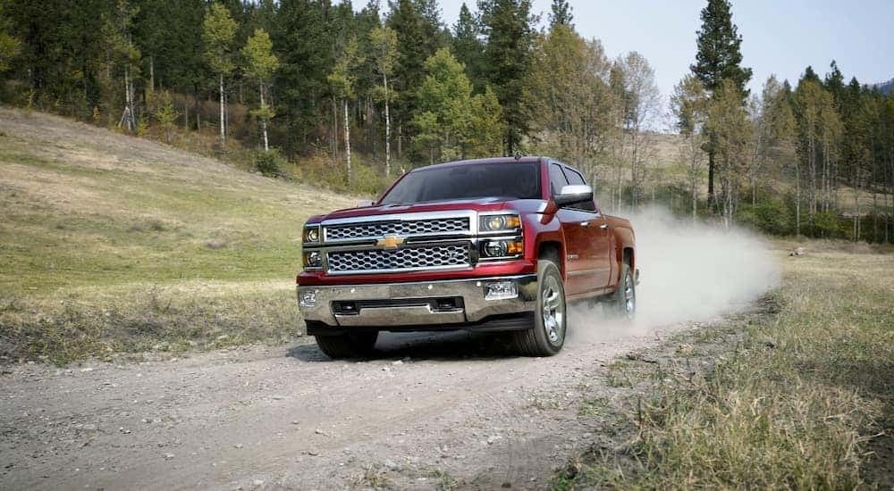 A red 2014 Chevy Silverado 1500 LTZ is shown kicking up dust on a trail