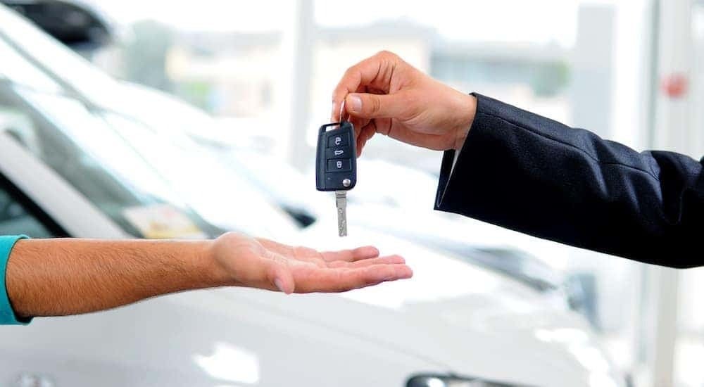Keys are shown exchanging hands at a dealership.
