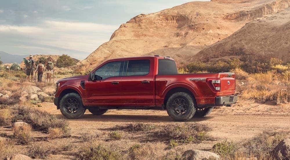 A red 2023 Ford F-150 Rattler is shown from the side while off-road