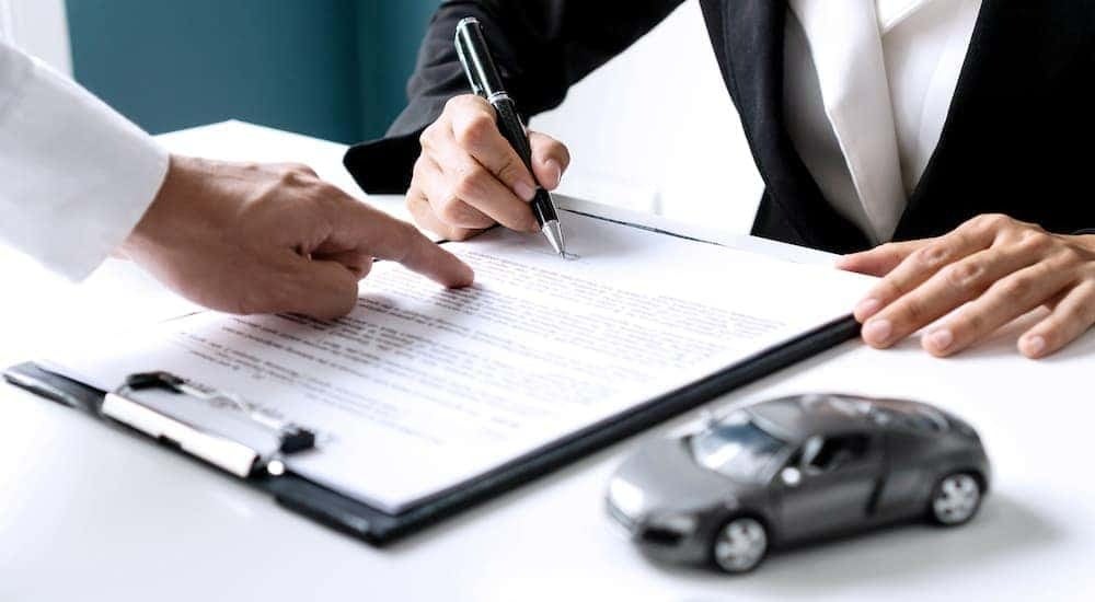 Someone is shown doing paperwork after researching how to 'sell my car'