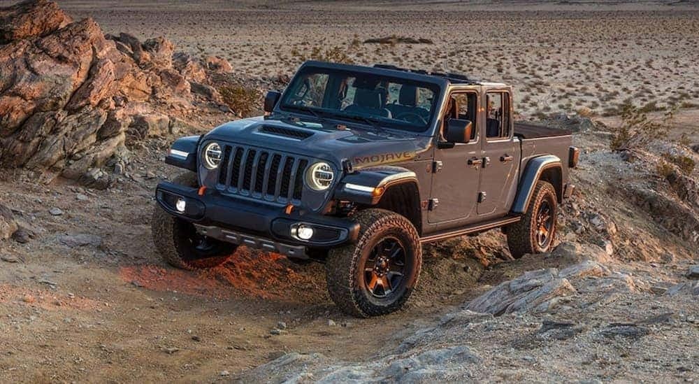 A grey 2021 Jeep Gladiator Mojave, a used truck for sale, off-roading in the desert.