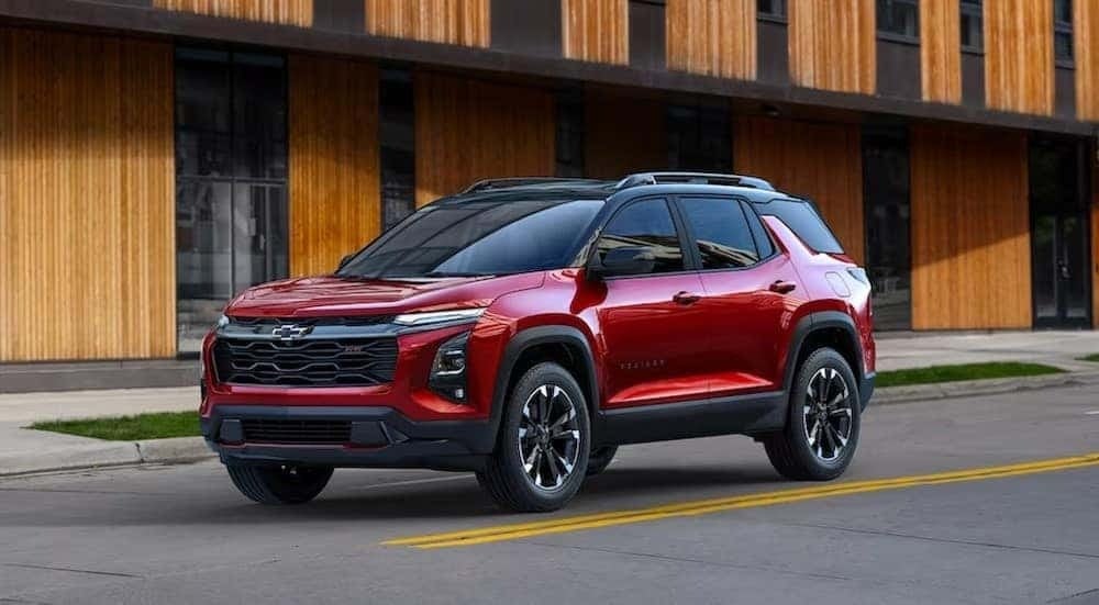 A red 2025 Chevy Equinox RS is shown driving on a city street.