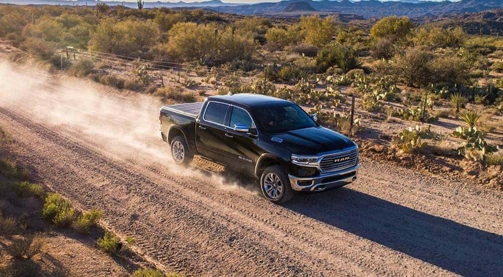 Aerial view of a black 2020 Ram 1500 driving on a dirt road.