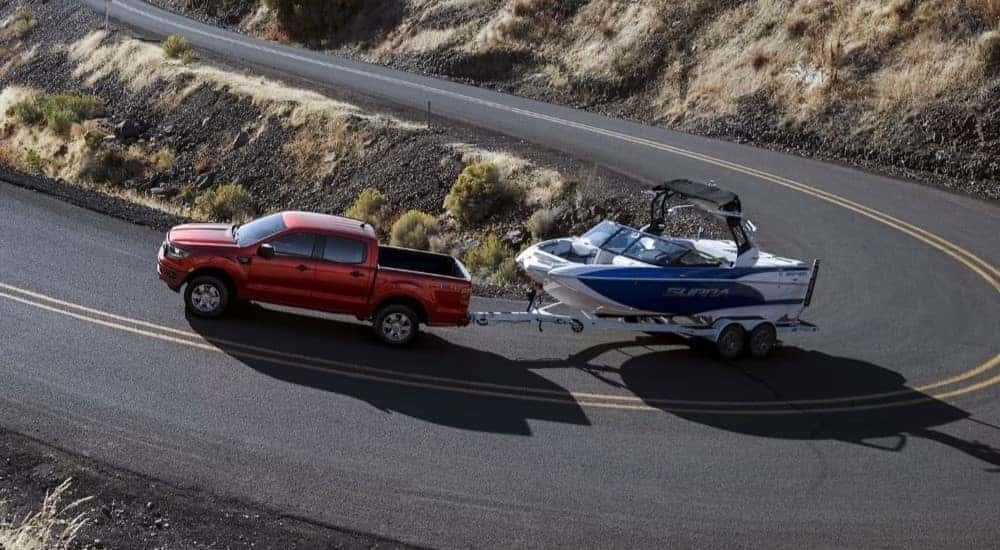 A red 2023 Ford Ranger XLT is shown towing a boat.