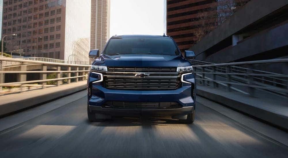 A blue 2023 Chevy Tahoe is shown driving to look at a used Chevy Tahoe for sale