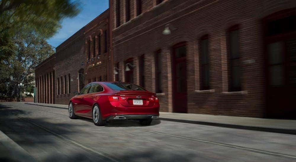 A red 2019 Chevy Malibu RS is shown from the rear after leaving a dealer that has cars for sale.