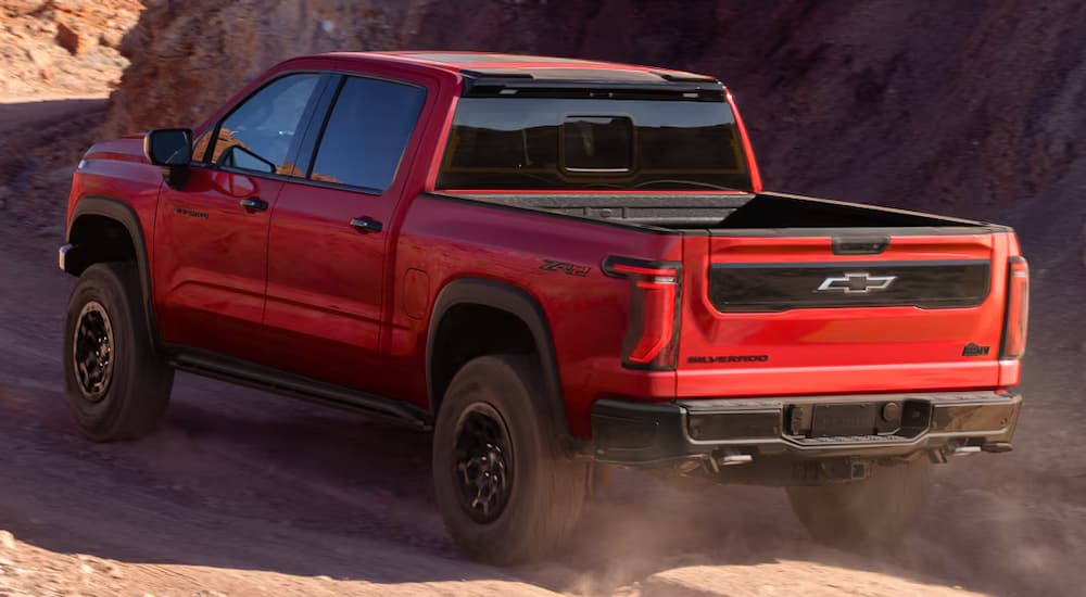 Rear of a red 2027 Chevy Silverado 1500 driving off-road