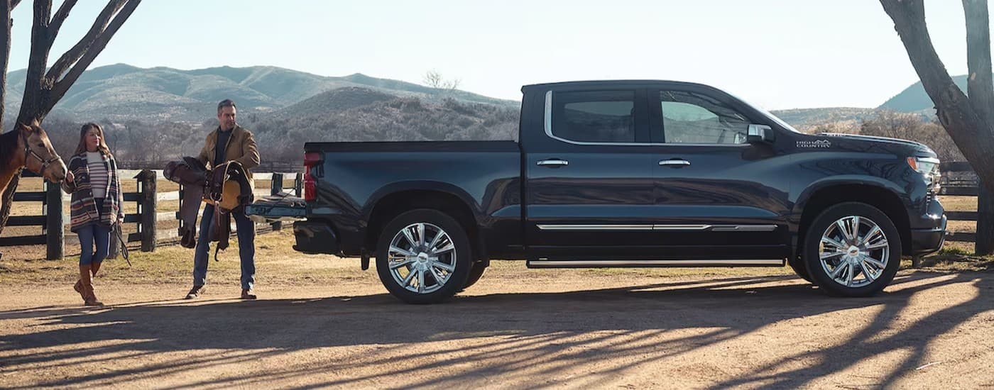 A black 2024 Chevy Silverado 1500 High Country parked on a farm.
