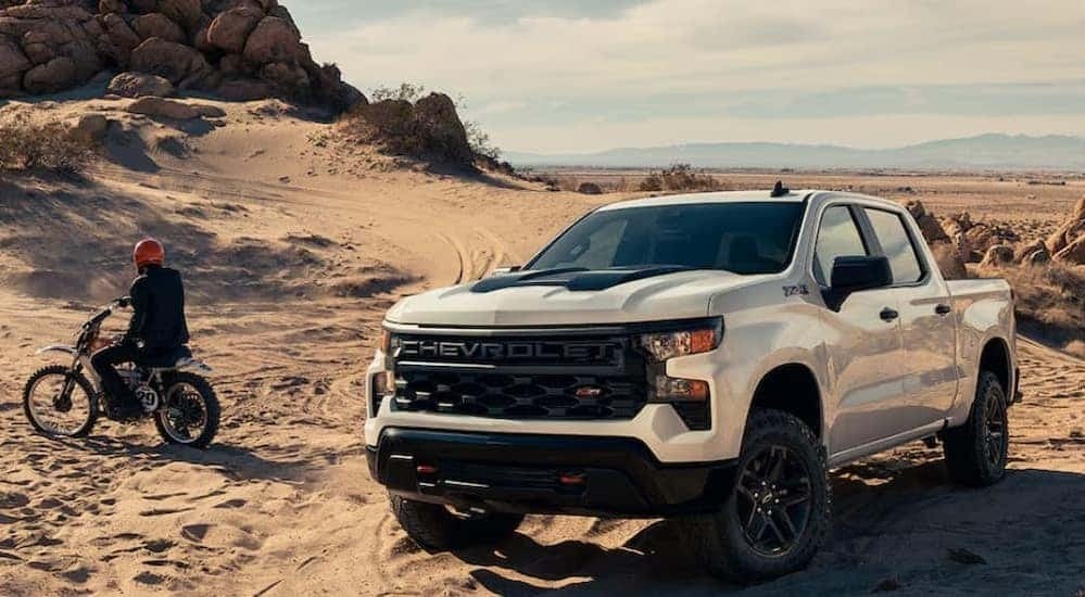 A white 2024 Chevy Silverado 1500 Z71 Custom Trail Boss is shown parked off-road.