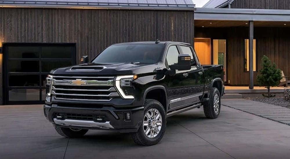 A black 2024 Chevy Silverado 2500 HD High Country is shown parked on a driveway.