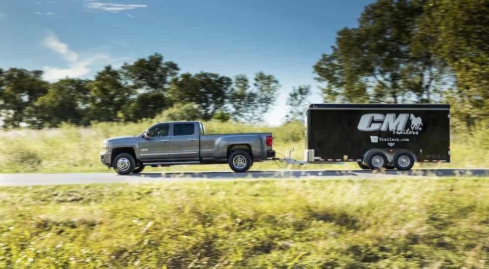 A grey 2017 Chevy Silverado 3500HD High Country is shown from the side towing a trailer.