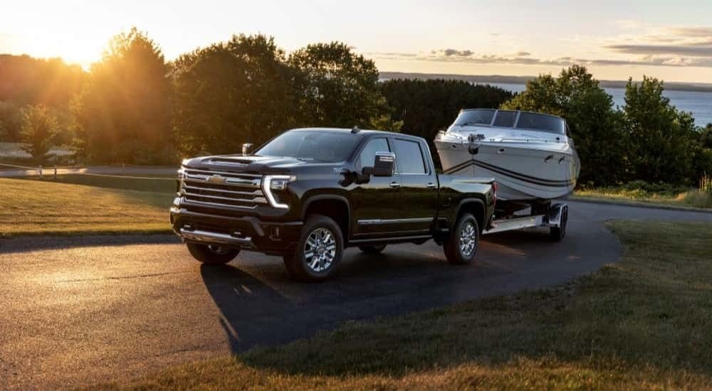 Black 2024 Chevy Silverado 2500 HD High Country towing a boat.