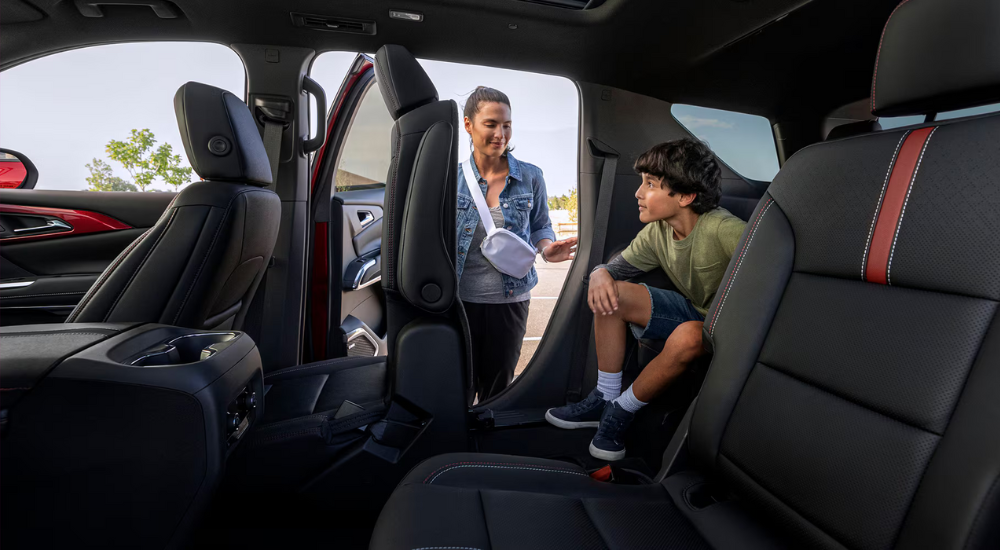 A parent putting a child in the third row of a 2026 Chevy Traverse