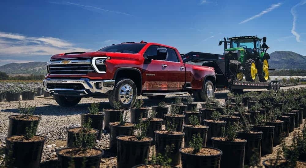 Red 2026 Chevy Silverado 2500 HD towing a tractor