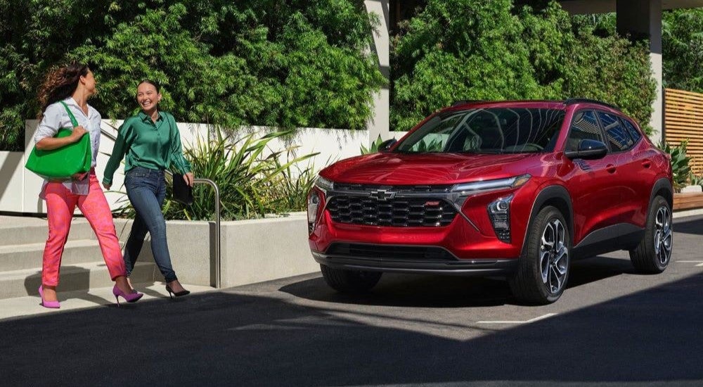 Red 2024 Chevy Trax RS is shown parked near two people walking