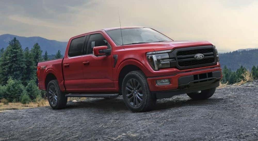 A red 2024 Ford F-150 Lariat parked on rocks while off-roading.