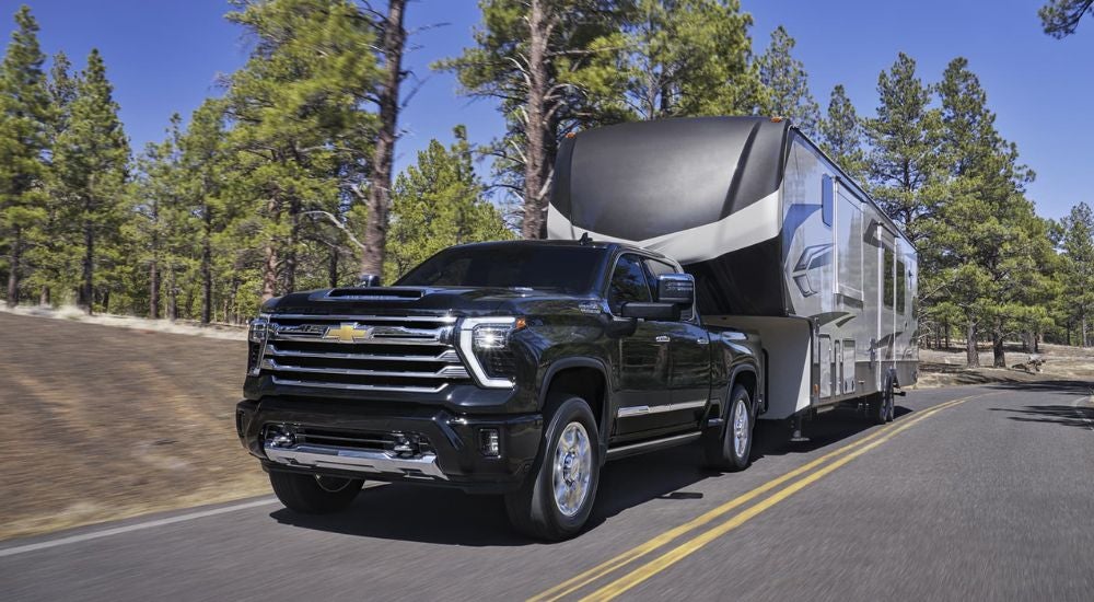Black 2026 Chevy Silverado 2500 HD towing a camper