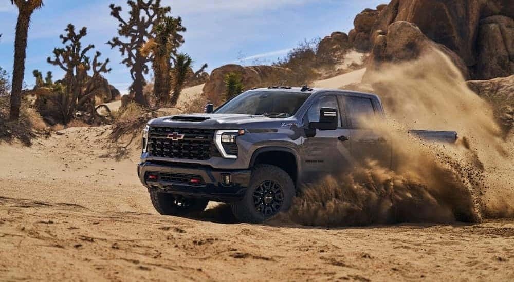 A popular Chevy Silverado 2500 HD for sale, a gray 2024 Chevy Silverado 2500 HD ZR2, is shown driving on sand.